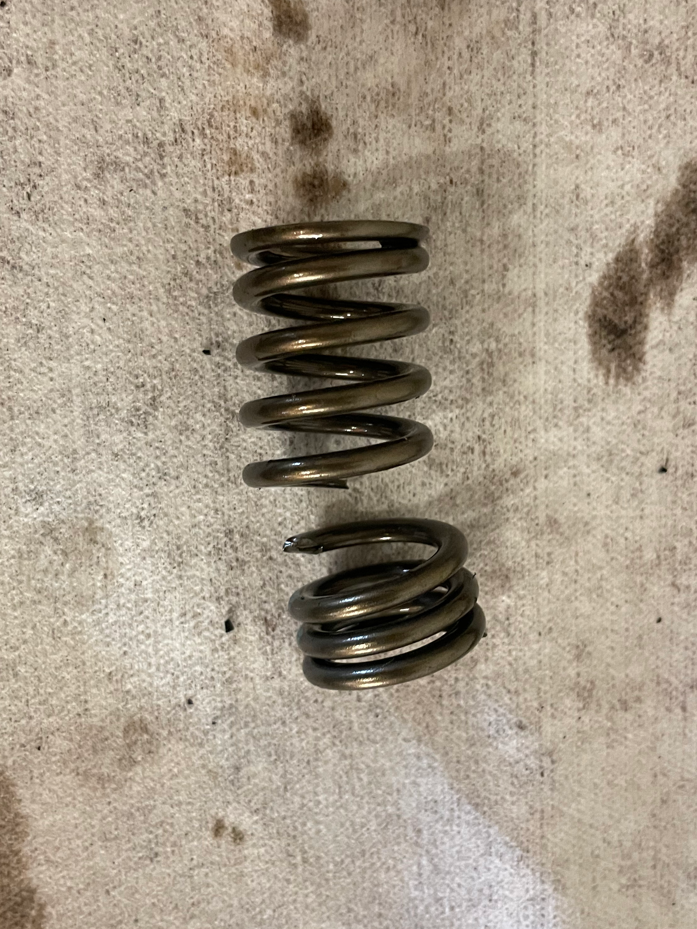 Broken valve spring removed and shown on the bench in two pieces