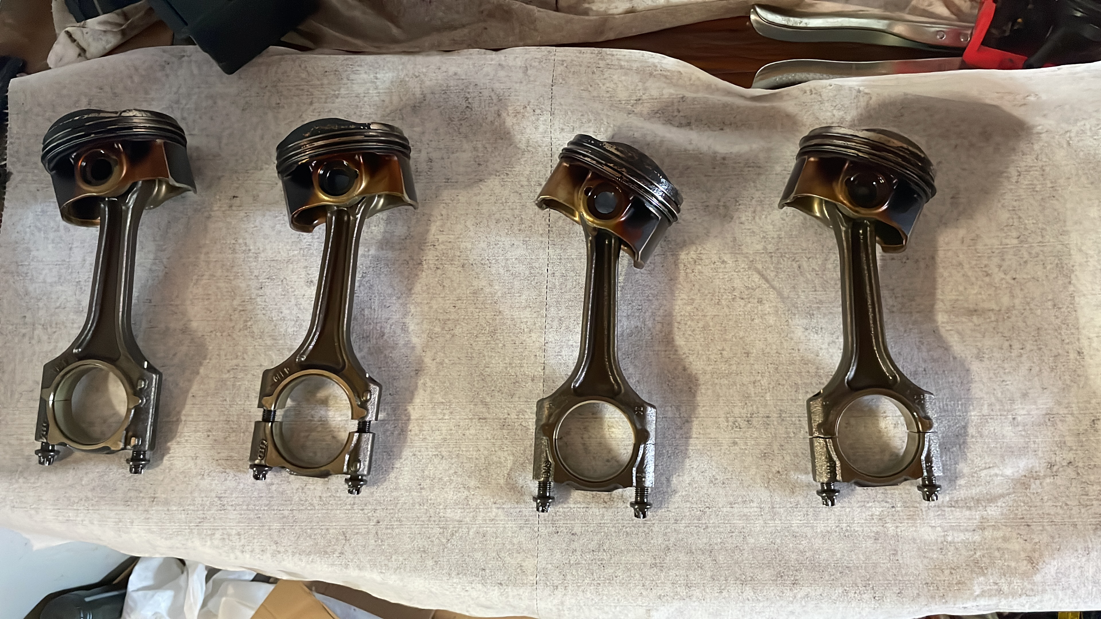 Pistons removed and laid out during disassembly for ring replacement and inspection