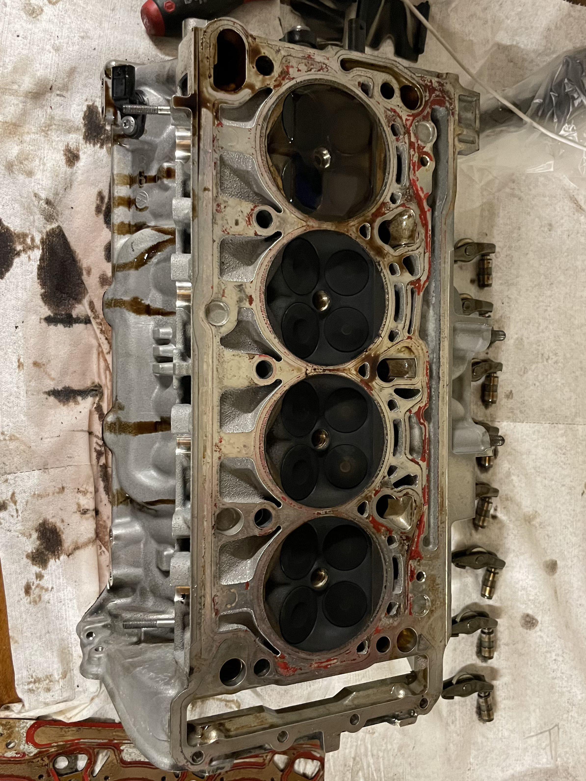 Removed cylinder head before cleaning, showing heavy residue from operation